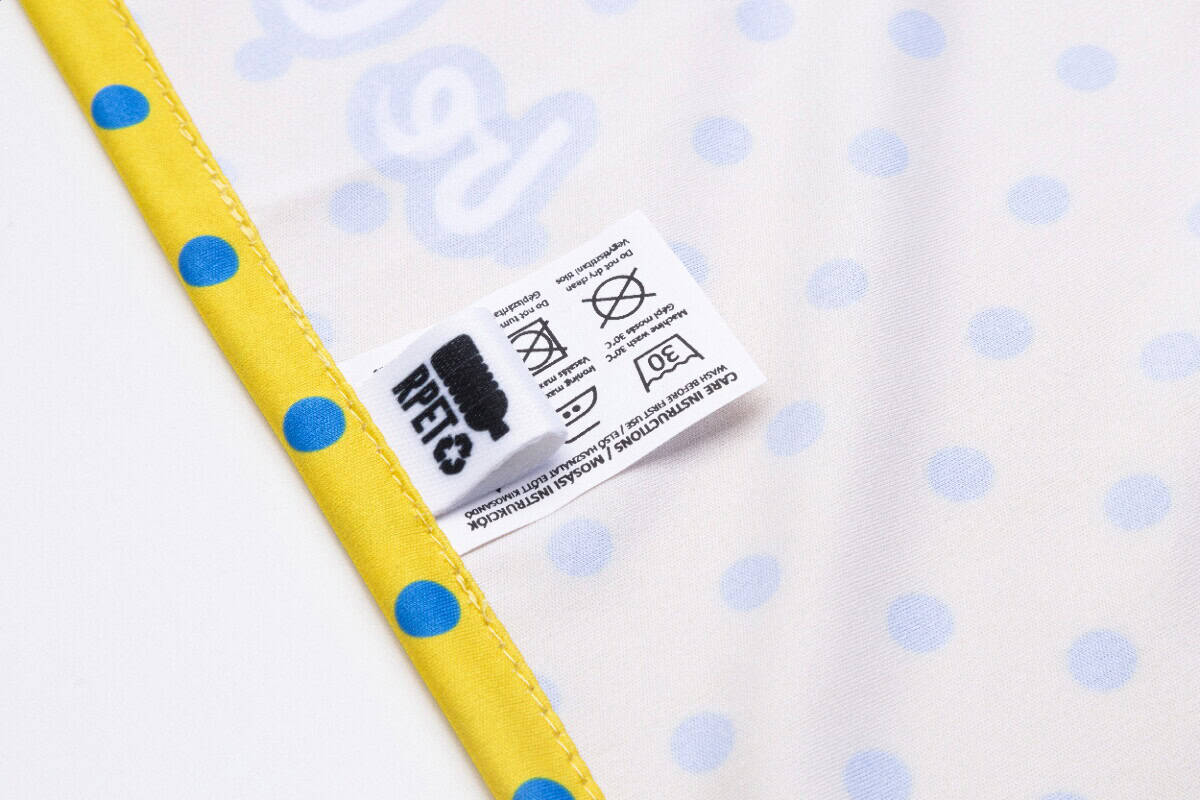 Gadżet na plażę lub basen. Etykieta z instrukcjami prania na tkaninie z nadrukiem w groszki.