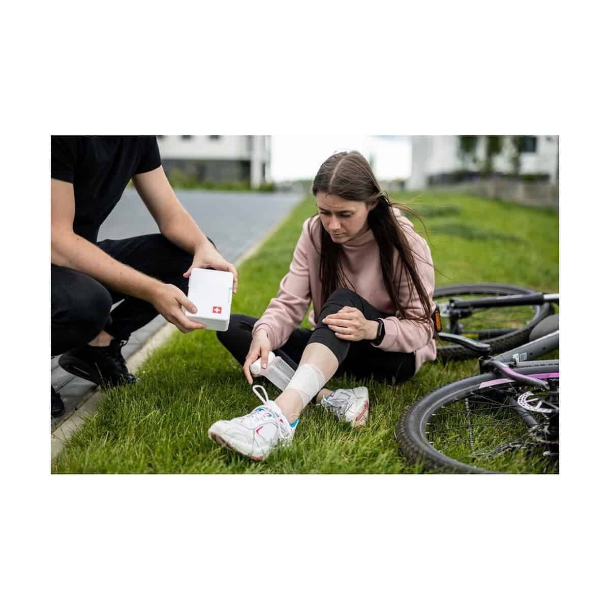 Apteczki z logo – apteczka w plastikowym opakowaniu, 64 el. | ramona V7249_A Opaska pierwszej pomocy na nodze kobiety, ratunek, uraz, sadzenie opatrunku, rower, pomoc medyczna, outdoor, bezpieczeństwo.