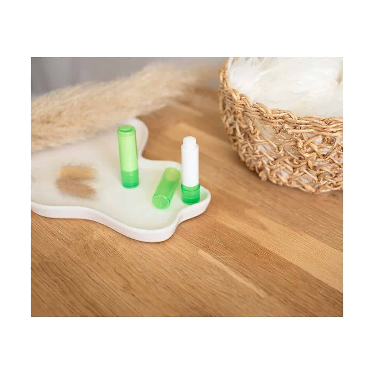 Balsamy do ust z logo – pomadka ochronna V4333_B 1. Pojemnik na pomadki w zielonym kolorze na drewnianym stole.