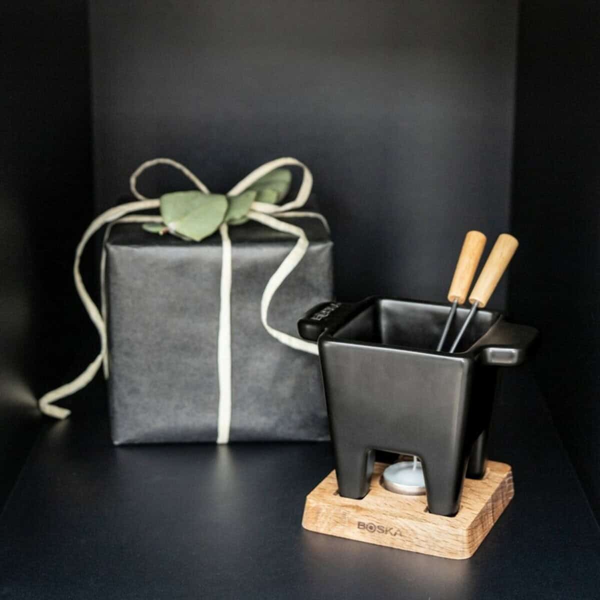 Gadżety do serwowania z logo – zestaw do serwowania fondue boska tapas fondue nero VSB13-03__M_418 Papierowa butelka z zieloną wstążką i czarny organizer na przybory biurowe na drewnianej podstawie.