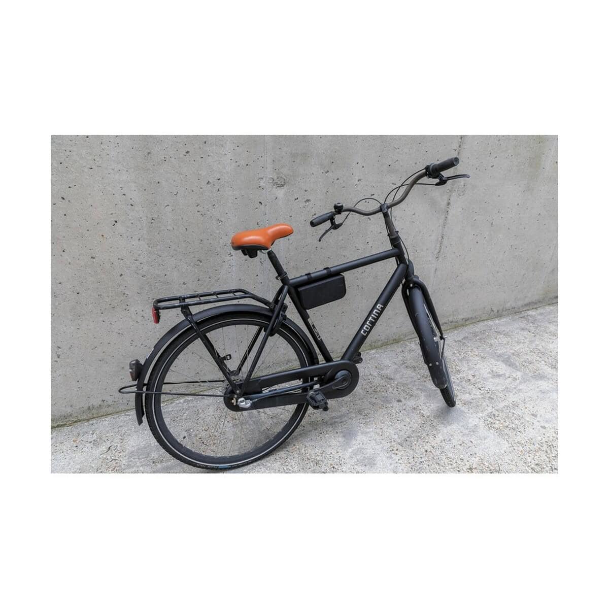 Gadżety rowerowe z logo – zestaw naprawczy do roweru P416.351__M_401 Rowery e-bike z czarnym ramą i brązowym siodełkiem na tle betonowej ściany.