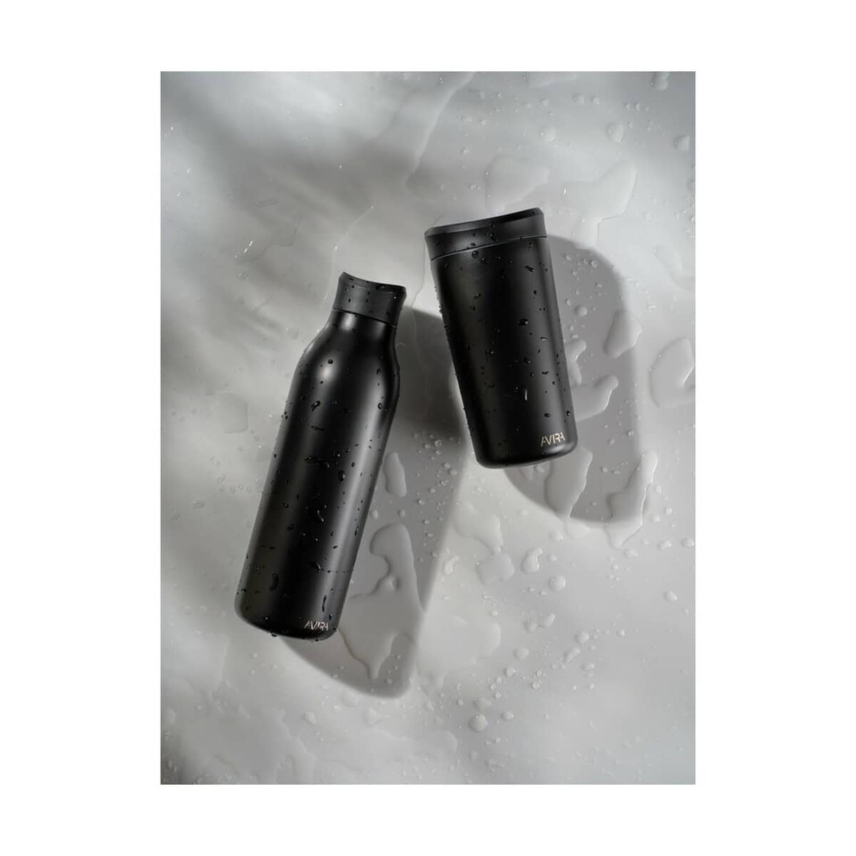 Kubki termiczne z logo – kubek termiczny 400 ml avira alix P438.1001__G_302 Opony termiczne czarne butelki na wodę marki AVIRA na mokrej powierzchni z kroplami wody.