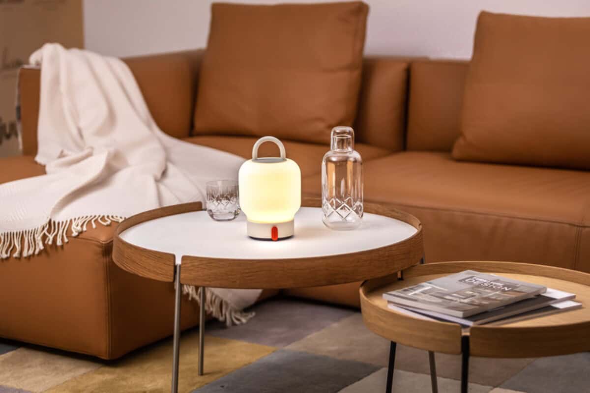 Lampki na biurko z logo – kooduu loome przenośna lampa 12445701_m1 Lampka LED na stoliku kawowym w salonie z brązową sofą i kieliszkiem wody.