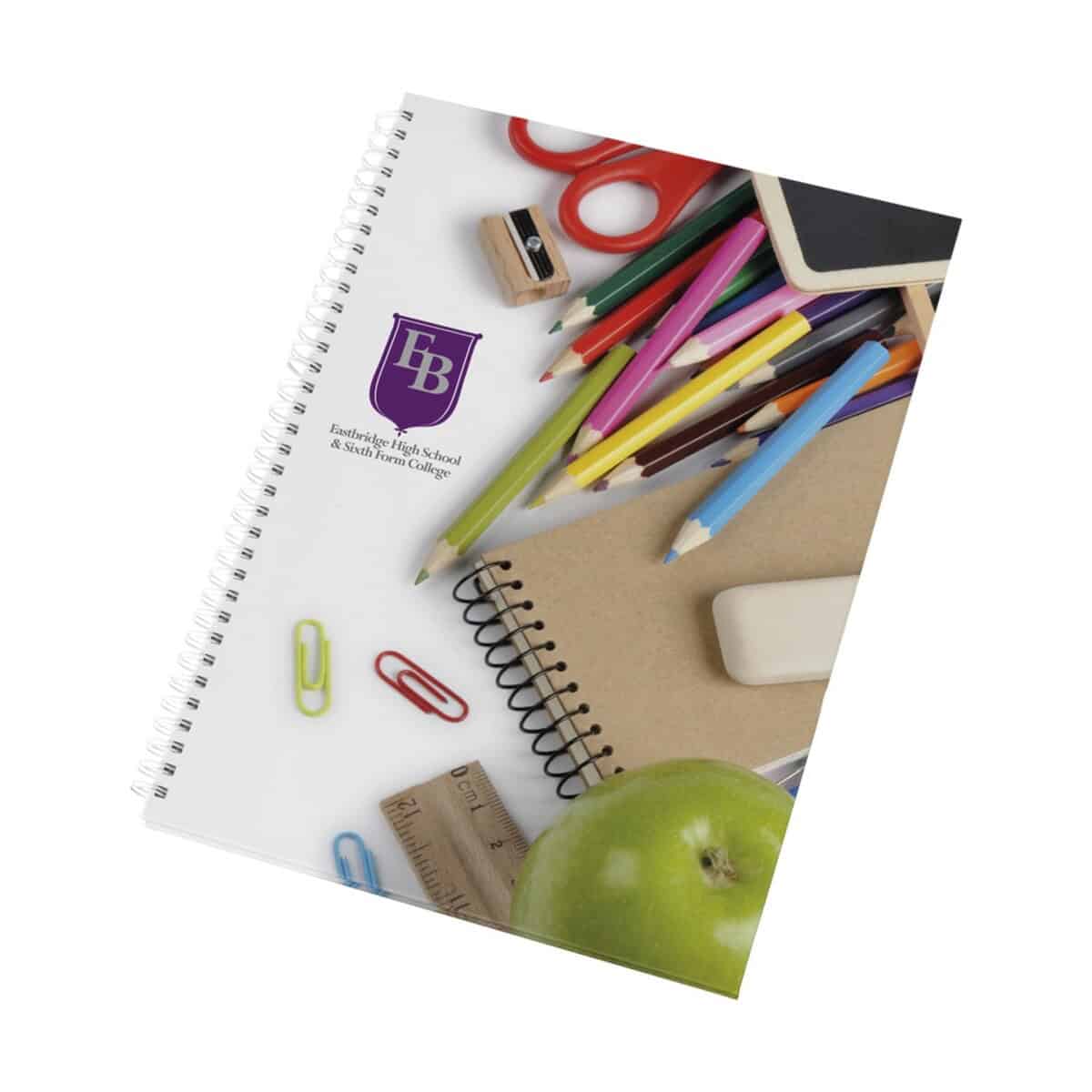 Kolorowe przybory szkolne na notatniku i płycie z logo szkoły. Akcesoria edukacyjne, biurowe i plastyczne do szkoły i biura.