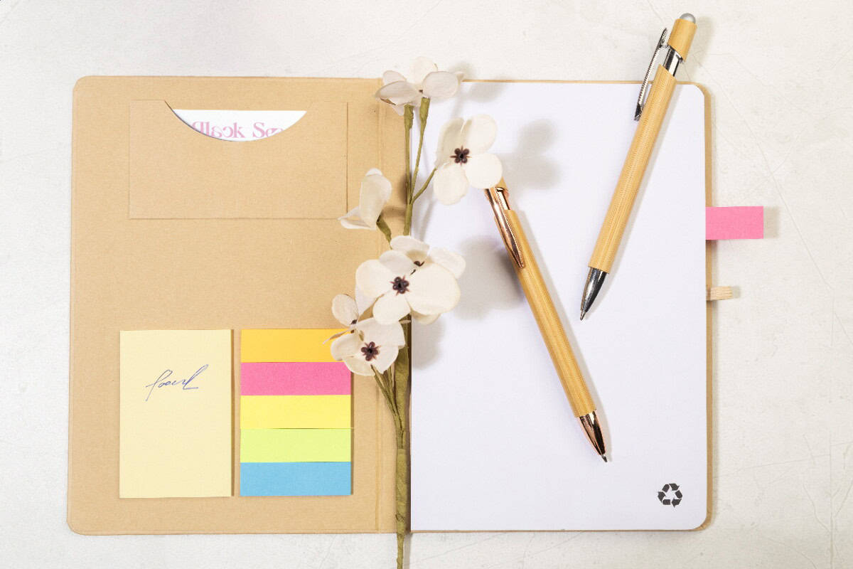 Notesy z logo – conus notes AP800097-00__DG2 Kolorowe gadżety biurowe i notatki na biurku z kwiatami, idealne do planowania i organizacji.