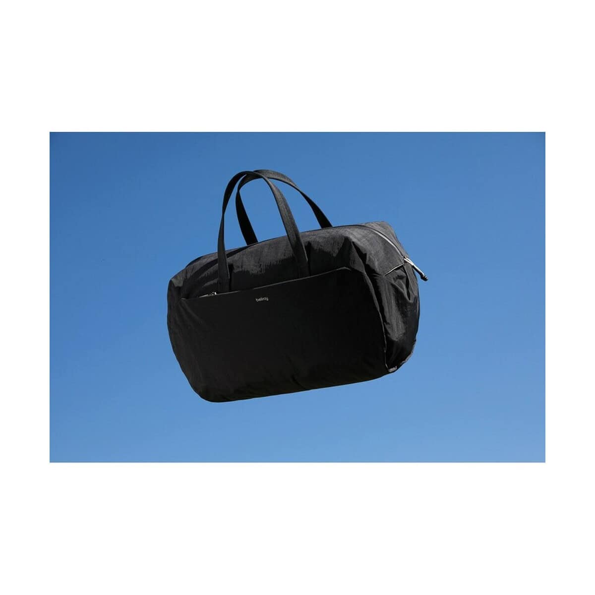 Torby podróżne z logo – torba podróżna, sportowa bellroy P763.3701__M_401 Czarna torba sportowa na niebieskim tle; idealne gadżety reklamowe i upominki promocyjne.