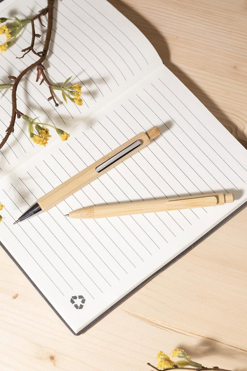 Notatnik z długopisem i kwiatami na drewnianym stole Notatnik z długopisem i kwiatami na drewnianym stole.